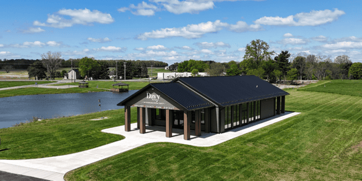 Exterior view of the Davy McClure Outdoor Education Center featuring a vaulted roof, Azek siding, large windows, and a canopy-covered patio surrounded by natural parkland.