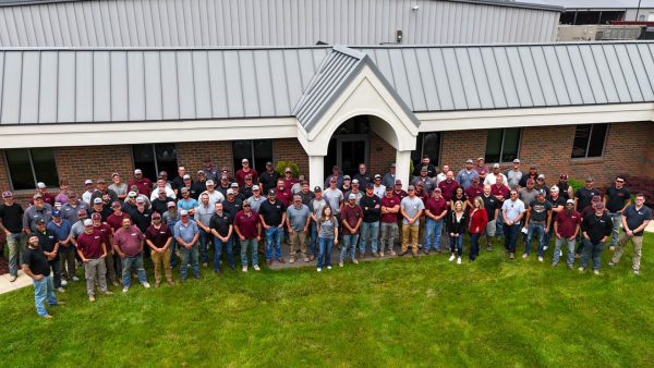 One hundred Simonson Construction Services, Inc employees stand in front of the company headquarters.
