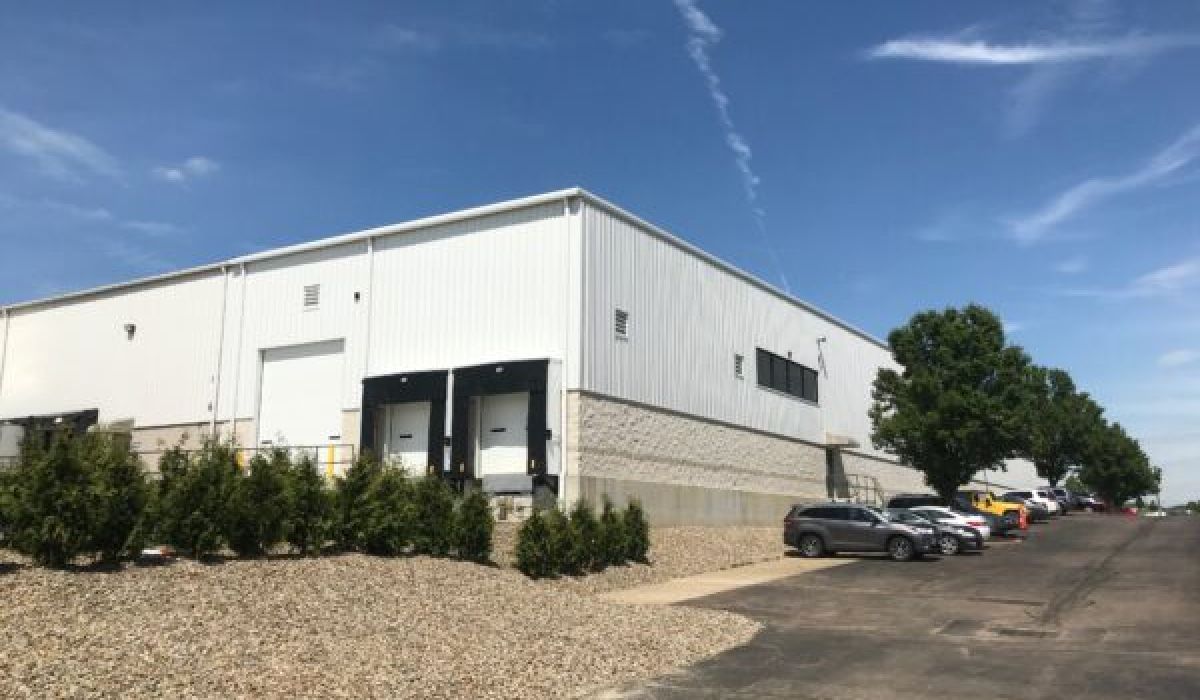 Pre-engineered metal building exterior that features three loading docks employee parking lot