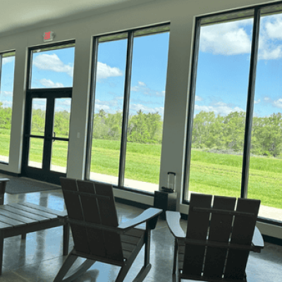 Seating area beside tall observation windows at the Davy McClure Outdoor Education Center, offering views of the forest and open landscape.