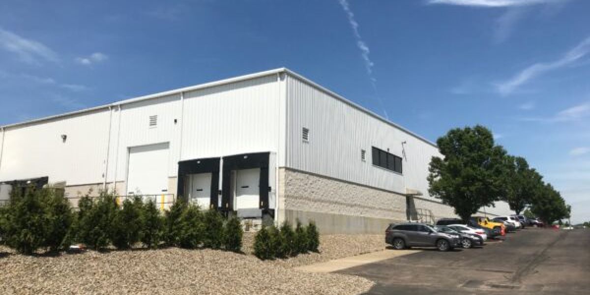 Pre-engineered metal building exterior that features three loading docks employee parking lot