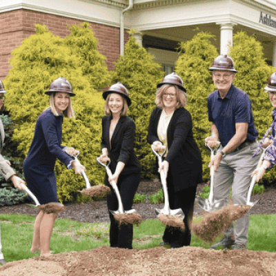The staff at the Ashland County Community Foundation are pictured in burgundy Simonson hard hats, holding shovels and a scoop of dirt during the philanthropic organization's groundbreaking ceremony for the Cutty Wing addition
