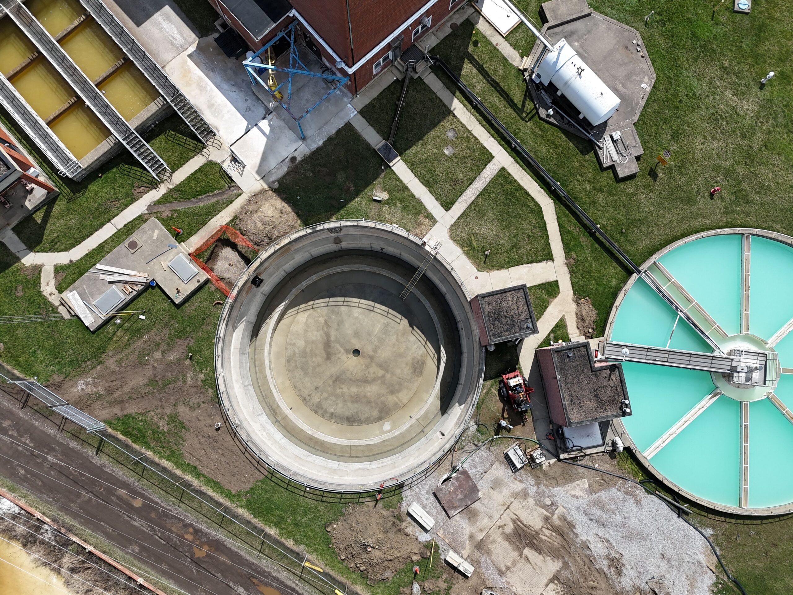 An aerial view of a round concrete water softener tank at a water treatment plant.