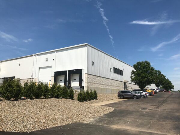 Pre-engineered metal building exterior that features three loading docks employee parking lot